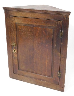 A 19thC oak hanging corner cupboard, the two panelled door with brass escutcheon and handle, 95cm high, 80cm wide, 40cm deep.