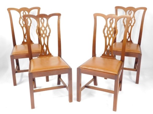 A set of four mahogany Chippendale style single dining chairs, each with a pierced splat, on H frame base, with tan leatherette drop in seats, 100cm high, 50cm wide.