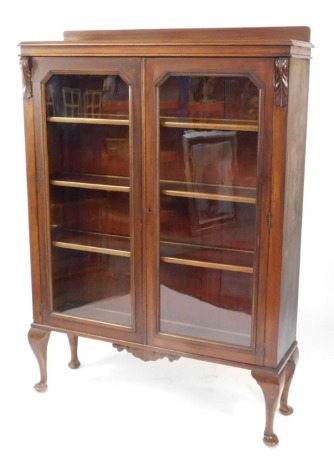 An early 20thC mahogany display cabinet, with two glazed doors enclosing three shelves, raised on cabriole legs, 162cm high, 114cm wide, 32cm deep.