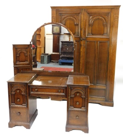 An early 20thC oak bedroom suite, comprising two door wardrobe, chest of drawers, and dressing table, each with reeded and carved detailing, the wardrobe 189cm high, 122cm wide, 50cm deep, the dressing table, with pie crust mirror, 145cm high, 120cm wide,