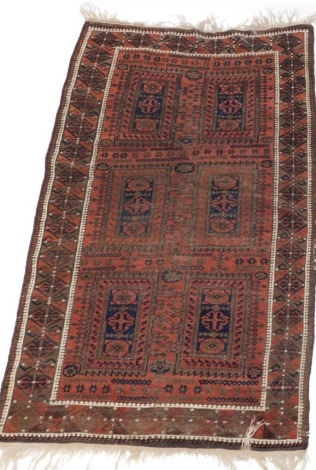 An Eastern bordered rug, rectangular panels, on a cream border, red ground with tassle ends, 200cm x 120cm.