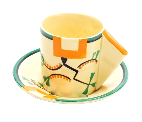 A Clarice Cliff Bizarre Ravel pattern coffee can and saucer, the coffee can with an angular handle, both pieces painted with an abstract design in green, orange and black against a pale yellow ground, printed marks, the can 5.7cm high, the saucer 10cm dia