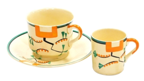 A Clarice Cliff Bizarre Ravel pattern teacup and saucer, each piece hand painted with an abstract design in green, orange and black against a pale yellow ground, printed marks, the cup 6.7cm high, the saucer 14.6cm diameter, and a further coffee can, 5.7c