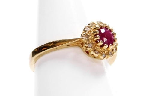 A 9ct gold ruby and diamond cluster ring, with central raised ruby approx 0.4cts, surrounded by twelve tiny diamonds, in a claw setting, ring size P½, 2.7g all in.