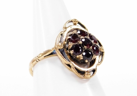 A 9ct gold garnet dress ring, the central cluster set with seven garnets, in Art Nouveau style, with etched shoulders, ring size N, 3.3g all in, boxed.