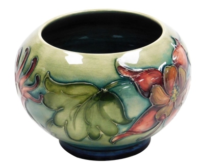 A Moorcroft pottery Columbine pattern vase, of squat bulbous form, printed marks and paper label, 8cm high.