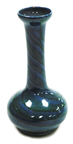 A Moorcroft pottery bottle vase, with a squat body and elongated neck with flared rim, decorated in a blue and green glaze, impressed marks, 21cm high.