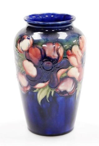 A Moorcroft pottery vase decorated in the Anemone pattern, against a cobalt blue ground, impressed and painted marks, bears paper label By Appointment, Potter to HM The Queen, 21cm high.