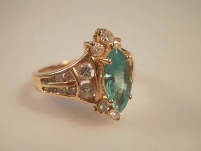 A marquise cut emerald 9.5mm x 4.5mm surrounded by ten diamonds with tiny