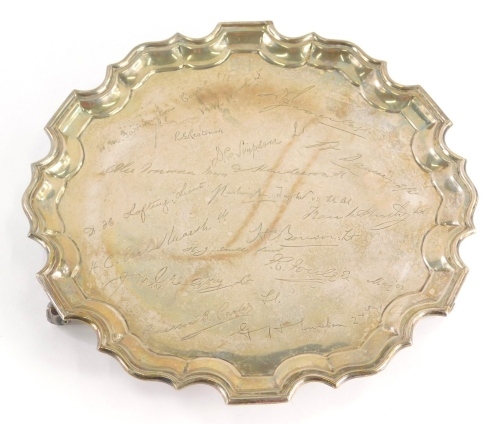 A George V silver salver, of piecrust form on triple scroll feet, set with a number of signatures include D H Lofting Lieut, other soldiers, Sheffield 1917, 26cm wide, 18oz.