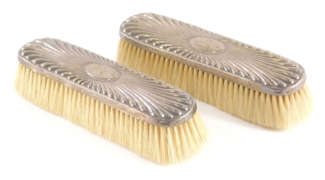 A pair of Victorian silver clothes brushes, with gadrooned decoration, each with a vacant cartouche, London 1890, 19cm wide.