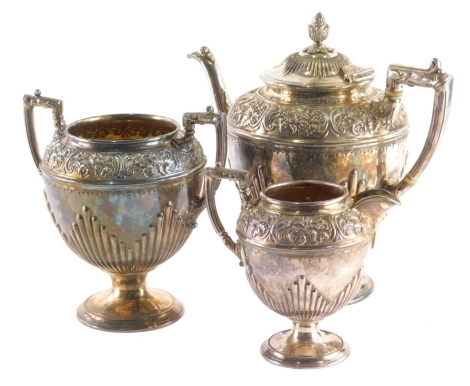 An early 20thC EPBM three piece coffee service, comprising coffee pot, 23cm high, milk jug, and two handled sugar bowl, each repousse decorated with scrolls and flowers, with part gadrooned decoration to the body on circular feet. (3)