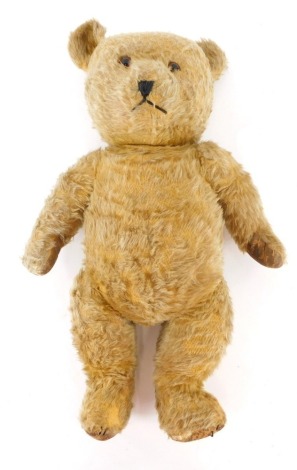 A mid 20thC English blonde plush jointed teddy bear, with glass eyes, fixed mouth, and articulated limbs, possibly Deans, unmarked, 54cm high.