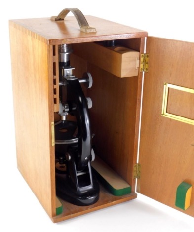 A metal student's microscope, in oak case with visible dove tails and leather handle, the case 41cm high.