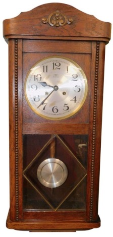 An early 20thC oak cased wall clock, with silvered 19cm Arabic dial, in a fitted case with visible pendulum and 8 day movement, 70cm high.