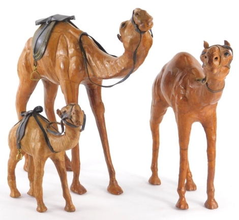 A graduated set of three leather covered style camels, 32cm high, etc. (3)