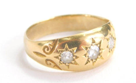 A gold ring, set with three diamonds in a textured shank, size K, 3.1g.