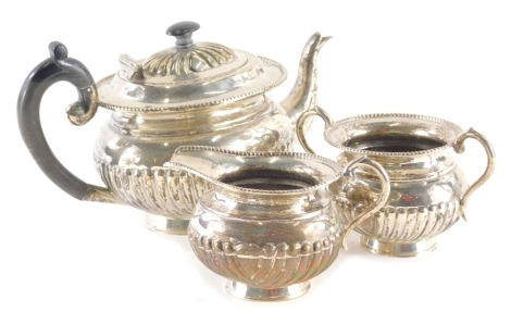 An early 20thC three piece tea service, comprising teapot, partially gadrooned of oval form with bead outline to the lid and ebonised thumb mould handle, 15cm high, with matching milk jug and sugar bowl, each marked sterling silver, possibly American (3).