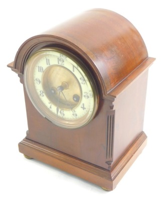 An Edwardian mahogany mantel clock, in domed case, the 12cm diameter Arabic dial revealing an 8 day movement, flanked by quarter columns on compressed bun feet, striking on the hour and half hours.