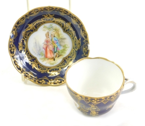 An early 20thC Vienna style cabinet cup and saucer, each hand painted with a courting couple on a dark blue ground with gilt highlights, beehive mark beneath, the saucer 12cm wide.