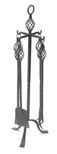 An Arts & Crafts style wrought iron fireside companion set, comprising a shovel, and three types of poker, 92cm high.