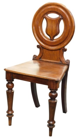 A Victorian mahogany hall chair, the circular back inset with a shield with a solid seat on turned tapering legs.