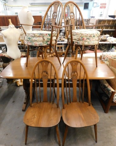 An Ercol elm rectangular dining table, with rounded corners on end supports, 74cm high, the top 83cm x 180cm, and six chairs each crest decorated with a swan, two with arms. The upholstery in this lot does not comply with the 1988 (Fire & Fire Furnishing