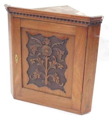 An Edwardian walnut hanging corner cabinet, the door carved with flowers and leaves, 64cm high, 60cm wide.