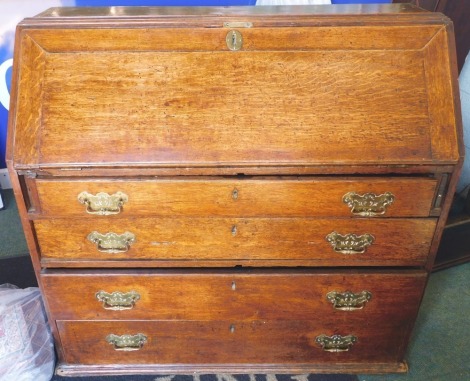 A George III oak bureau, the fall enclosing a fitted interior above four graduated drawers with later brass handles, 96cm high, 101cm wide. (AF)