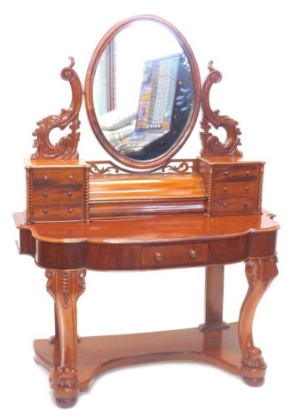 A Victorian walnut Duchess style dressing table, the oval mirror with shaped carved supports above two banks of three trinket drawers, each with bobbin turned supports, flanking a central hinged compartment, the base with a shaped front above a frieze dra