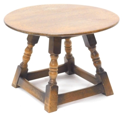 An oak coffee table, the circular top with a rounded edge, on turned supports, 38cm high, 55cm wide.