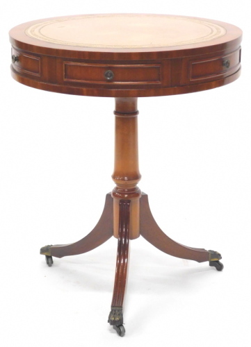 A mahogany drum table, the circular top with a brown leather section, above two drawers and four false drawers, on a turned column and tripod base, 60cm high, 50cm diameter.
