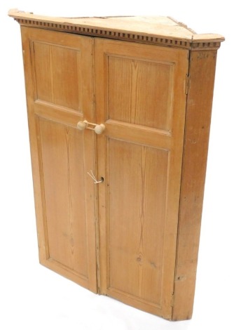 A 19thC pine hanging corner cabinet, with a dentil cornice above two panelled doors, 106cm high, 81cm wide, 42cm deep.