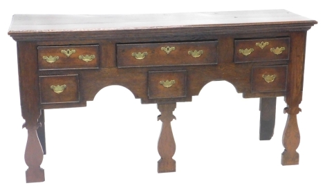 An 18thC oak dresser, the rectangular top with a moulded edge, above an arrangement of six drawers, each with engraved brass drop handles, with shaped apron and vase shaped front legs, 83cm high, 160cm wide, 46cm deep.