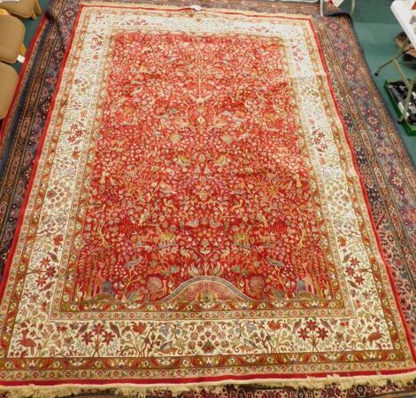 A red ground full pile Cashmere carpet, decorated with a tree of life, birds, animals, etc., with one wide and various narrow borders, 330cm x 240cm.