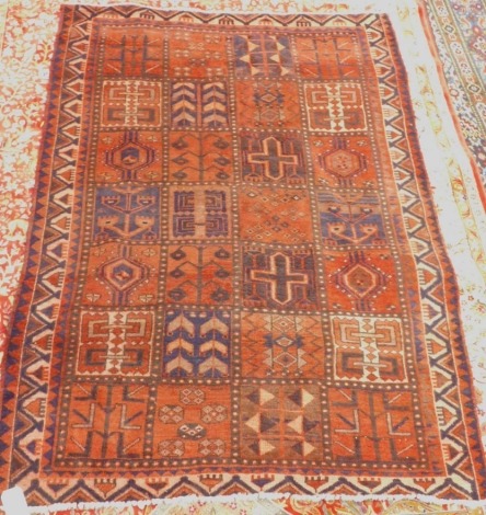 A washed red ground Persian Hammadan village rug, with a design of geometric devices within square shaped compartments, one wide and two narrow borders, 220cm x 150cm.