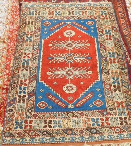 A Turkish rug, with a central pole medallion, on red ground with blue spandrels, surrounded by multiple geometric borders, 203cm x 137cm.