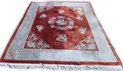 A large Chinese rug, of rectangular floor rug with a red centre and cream border, raised with flowers, 320cm x 237cm.