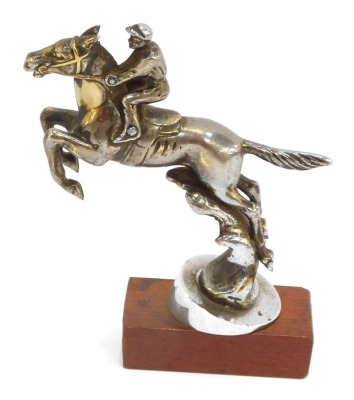 A Desmo brass and chrome finish car mascot, of a horse jumping the fence with jockey, on later applied wooden base, 17cm high.