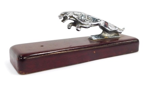 A Jaguar car mascot, mounted on a wooden plinth, the mascot 12cm wide, plinth 20cm wide.