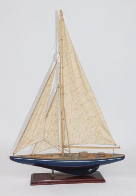 A wooden model of a racing yacht, on an integral base, 61cm wide.