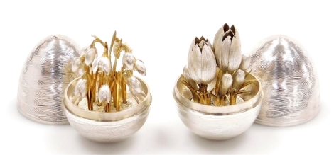 Two Elizabeth II silver eggs, decorated with engraved waved banding, the interior enclosing silver and gilt metal tulips, the other with snow drops, Peter Nicholas and Co, London 1999 and 1990, each 6cm high, 3¾oz and 2¾oz respectively.