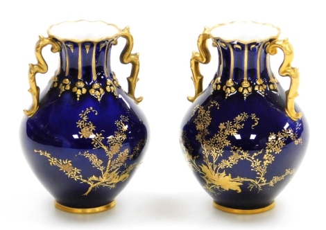 A pair of Royal Crown Derby porcelain vases, circa 1907, with gilt decoration of blossom against a cobalt blue ground, printed marks, 8.5cm high. (AF)