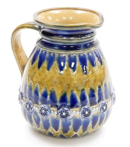 A Doulton Lambeth pottery jug, in green and blue glaze with raised floral and bead decoration, 14cm high.