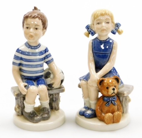 Two Royal Copenhagen porcelain Millennium models, of a boy with ball seated on a bench and a girl with teddy bear, Frederik and Emma, printed marks, each 10cm high. (2)