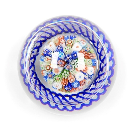 A Baccarat millefiori glass paperweight, with radial blue twist and lace canes, within a cobalt blue and white latticino torsade, with star cut base, 7cm diameter.