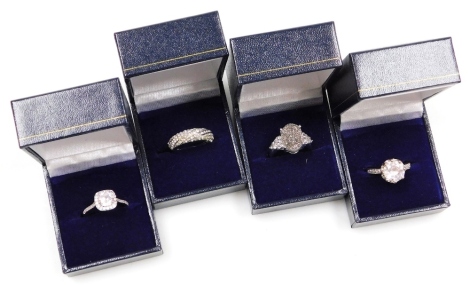 Four silver dress rings, comprising a halo ring, solitaire ring, crossover ring and a glitter applied dress ring, all marked 925, boxed. (4)