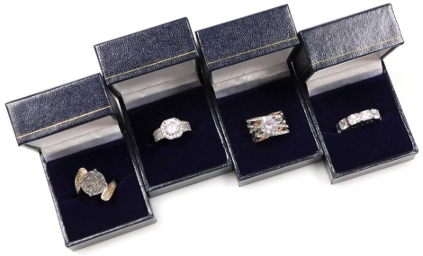 Four silver dress rings, each with imitation diamond, comprising an eternity ring, a cluster ring, bicoloured crossover ring, and a glitter applied dress ring, each stamped 925, boxed. (4)