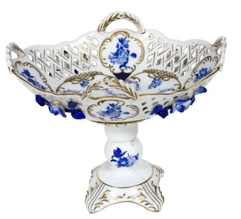 A Continental porcelain blue and white comport, of four handle basket form, raised on a double knop stem over a quatrelobe base, painted with reserves of flowers, 24cm wide.