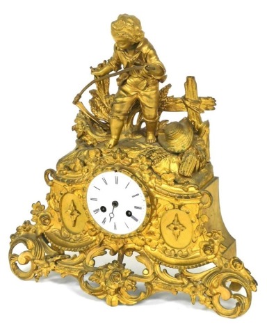 A 19thC French gilt metal mantel clock, circular enamel dial bearing Roman numerals, eight day movement with bell strike, the case of scrolling rococo form, surmounted with a boy against a fence reaping wheat with a scythe, 36cm high.